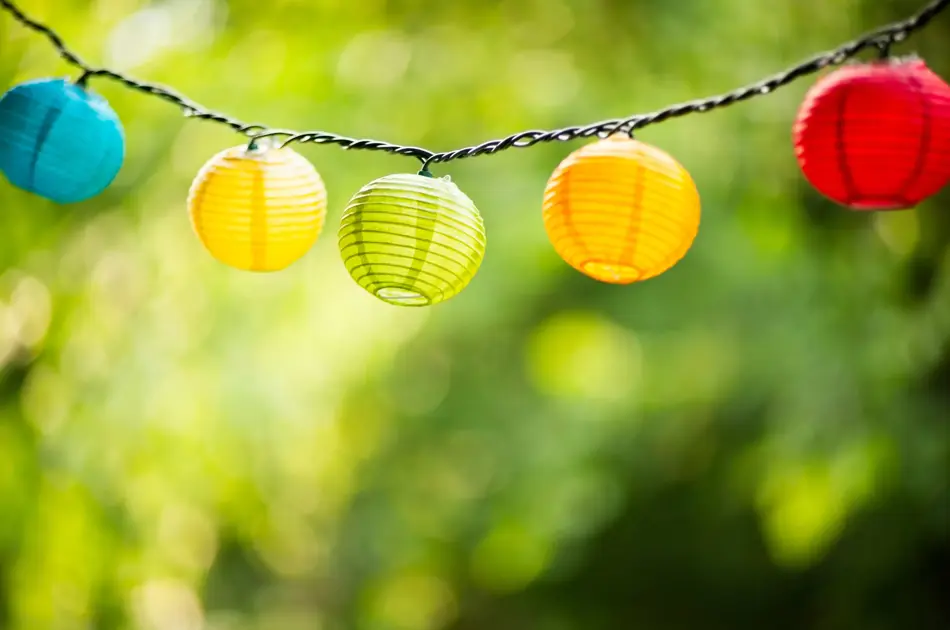 Lyslenke med papirkuler i forskjellige farger på en grønn bakgrunn