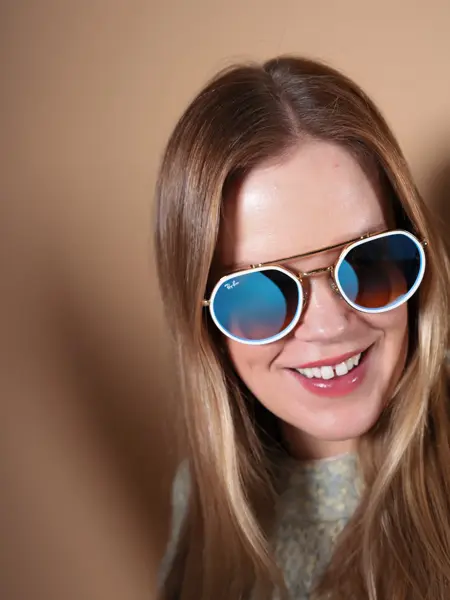 Dame med RayBan solbriller med hvit ramme rundt glassene