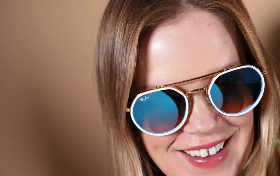 Dame med RayBan solbriller med hvit ramme rundt glassene