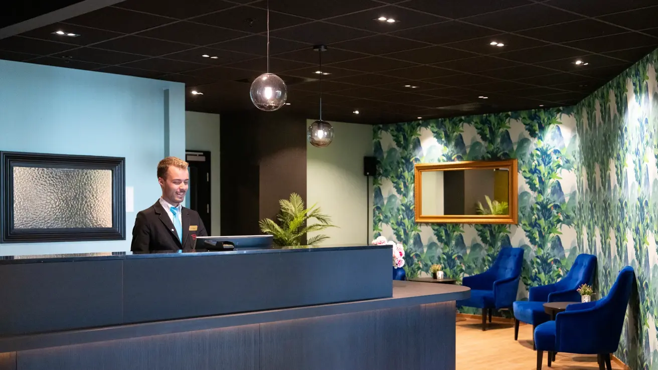 Resepsjonist står bak resepsjonsdisk på Thon Hotel Verdal.