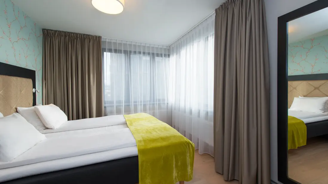 Dobbeltseng med speil på juniorsuite påThon Hotel Slottsparken i Oslo sentrum rett ved Karl Johan