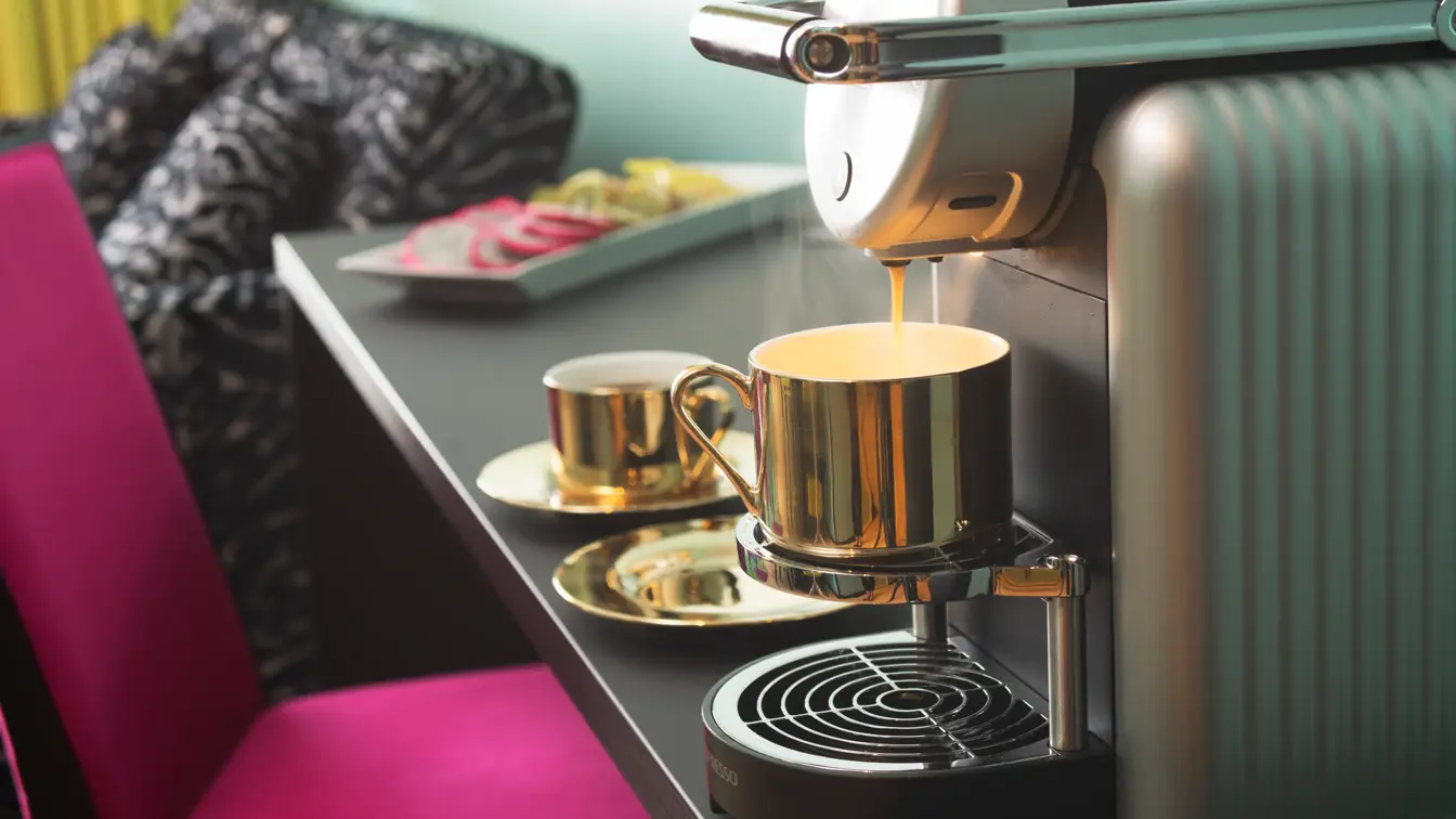 Skrivepult med kaffemaskin, lilla stol og zebramønstret sofa ved siden av på suite på Thon Hotel Terminus i Oslo sentrum nær Jernbanetorget