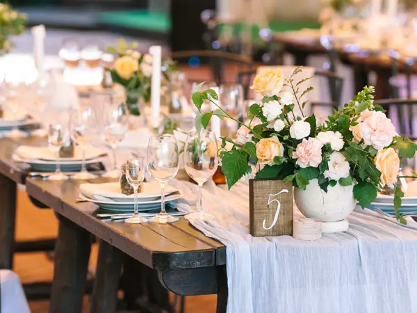 holiday, excitement, serving concept. there are untouched white dishes, clear wineglasses, silverware and gorgeous bouqets of roses avalanches on the table numbered five