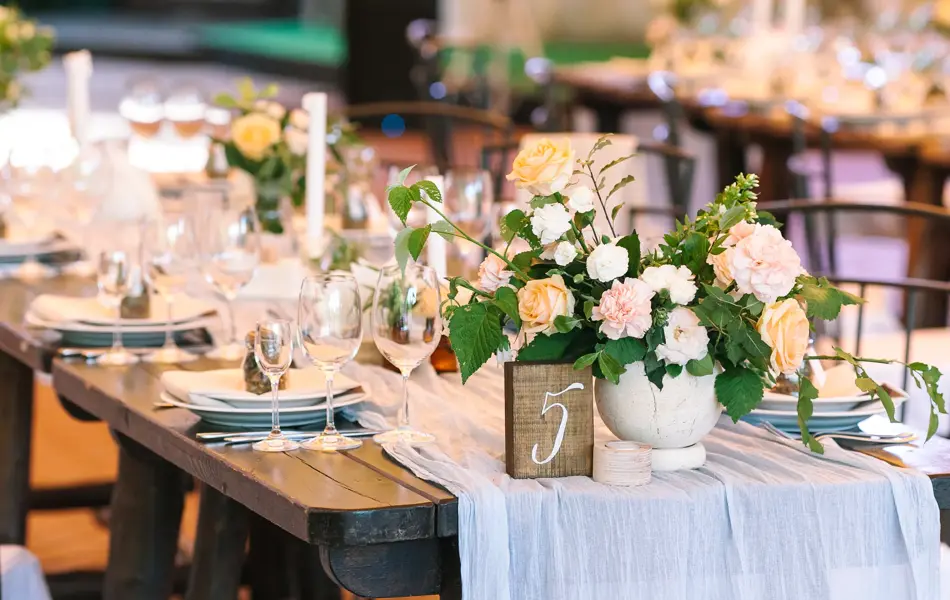 holiday, excitement, serving concept. there are untouched white dishes, clear wineglasses, silverware and gorgeous bouqets of roses avalanches on the table numbered five