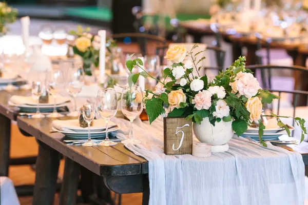 holiday, excitement, serving concept. there are untouched white dishes, clear wineglasses, silverware and gorgeous bouqets of roses avalanches on the table numbered five