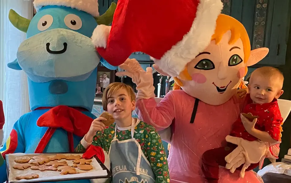 Amfelia og Oskar sammen med to barn, holder opp et brett med pepperkaker