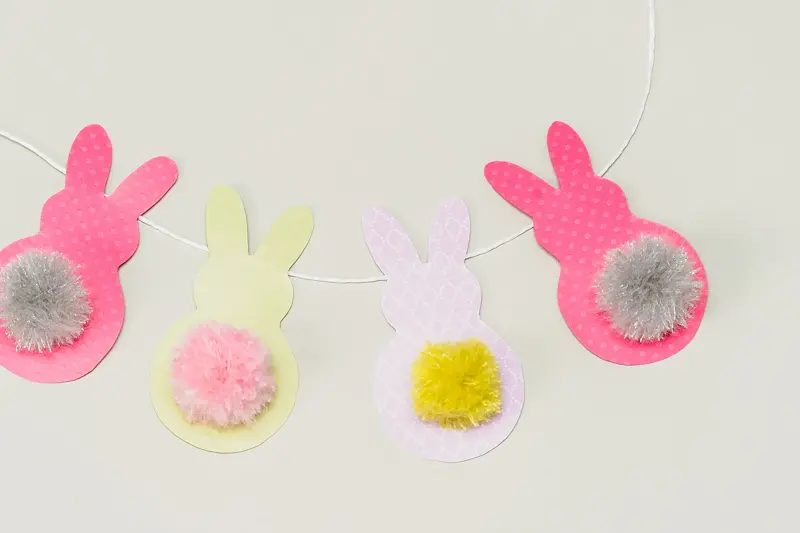 Fire påskeharer klippet i papir på en hvit snor