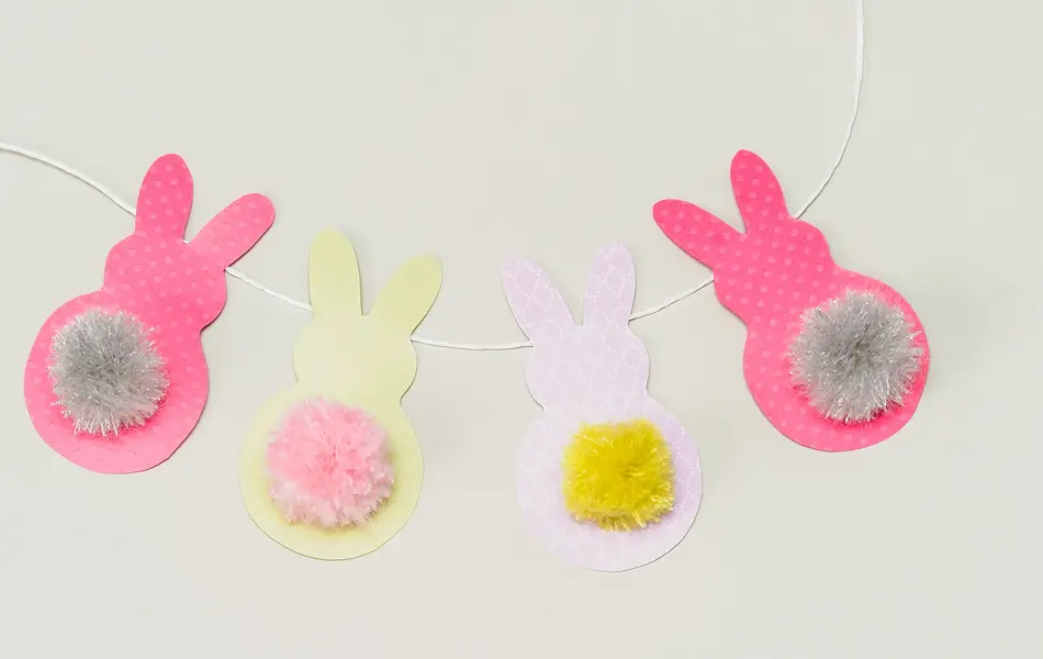 Fire påskeharer klippet i papir på en hvit snor