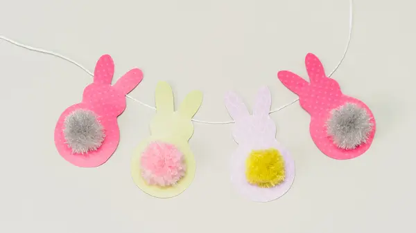 Fire påskeharer klippet i papir på en hvit snor