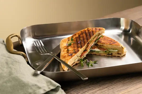 En dame som holder på med oppussing og tips om interiør trender for våren 2021. Damen har lyst halvlangt hå og har på seg en blå olaskjorte og blå olabukse. Fargene går i brunt og beige jordtoner og det er mye lilla og pastellfarger. Vårens interiør