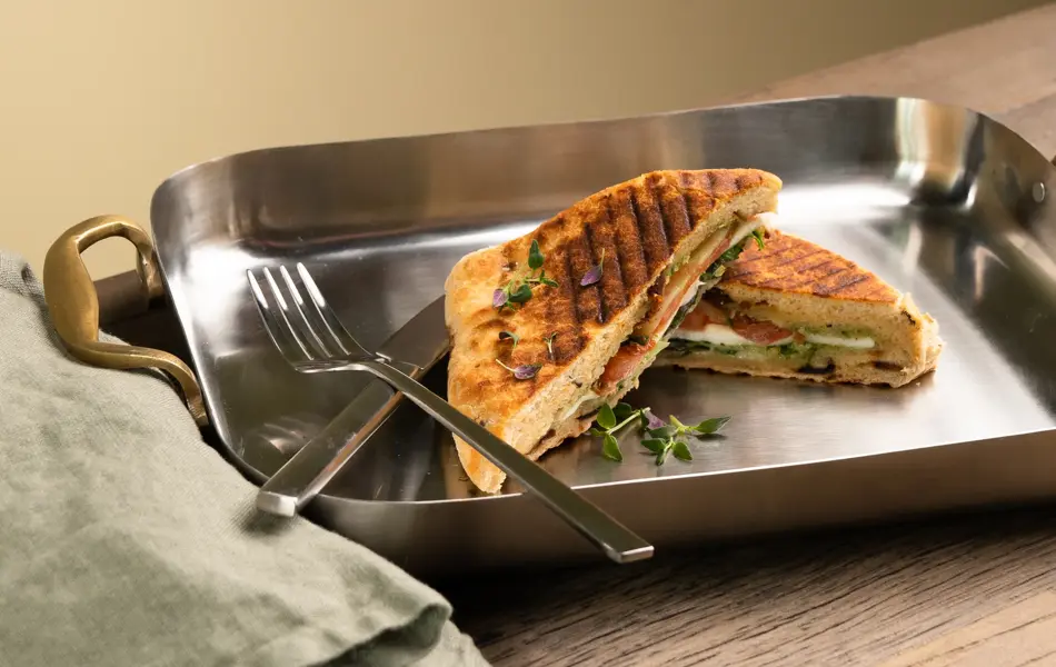 En dame som holder på med oppussing og tips om interiør trender for våren 2021. Damen har lyst halvlangt hå og har på seg en blå olaskjorte og blå olabukse. Fargene går i brunt og beige jordtoner og det er mye lilla og pastellfarger. Vårens interiør