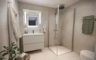 3D illustrasjon av et bad i boligprosjektet Skårerløkka PREMIUM på Lørenskog. Badet har store, moderne fliser. Et dusjhørnet med glassvegger, samt et servantskap i beige. Lyst og lekkert bad med godt lys.