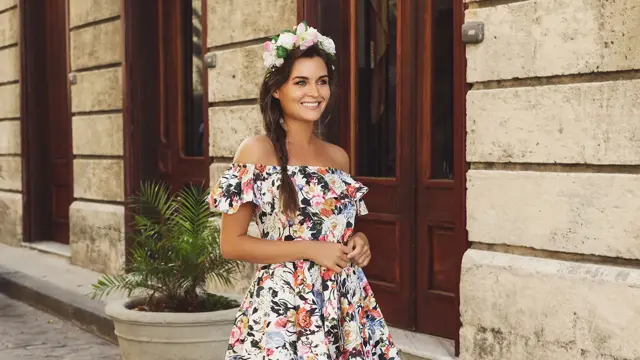 Dame med brunt flettet hår med blomsterkrans i kort blomstrete kjole