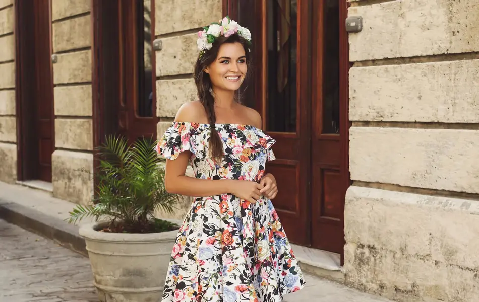 Dame med brunt flettet hår med blomsterkrans i kort blomstrete kjole