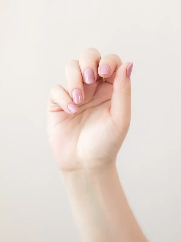 Nærbilde av hånd med dus, lys rosa neglelakk 