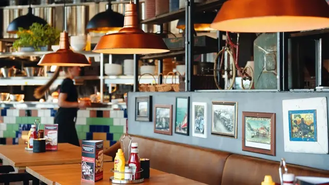 Sitteplasser i restaurant, messinglamper og bilder på vegg