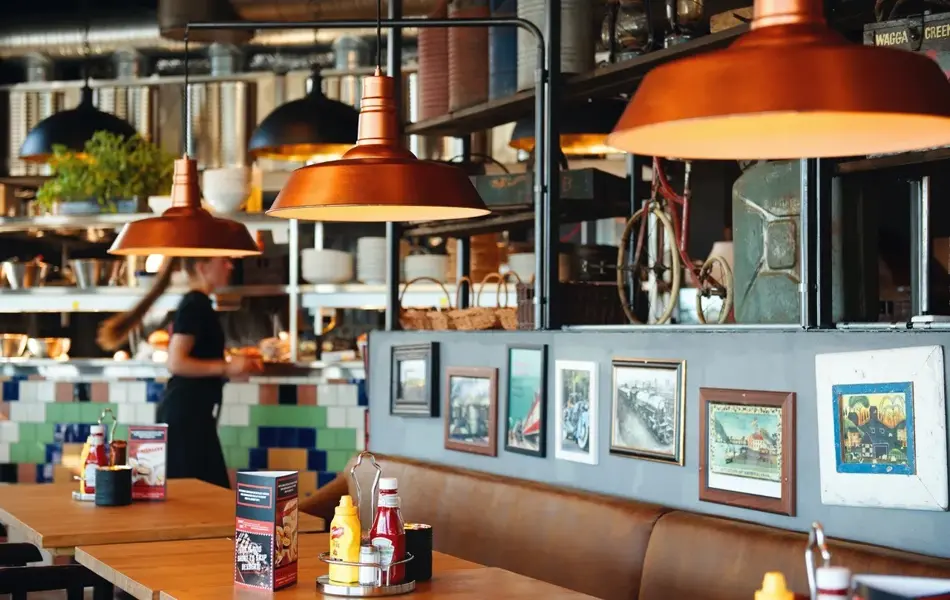 Sitteplasser i restaurant, messinglamper og bilder på vegg