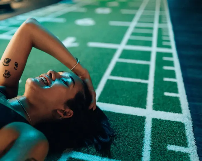 smilende svett dame som ligger på gulvet i et treningssenter i sort sportsbh