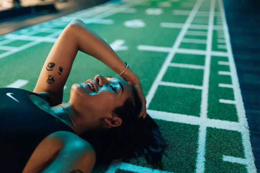 smilende svett dame som ligger på gulvet i et treningssenter i sort sportsbh