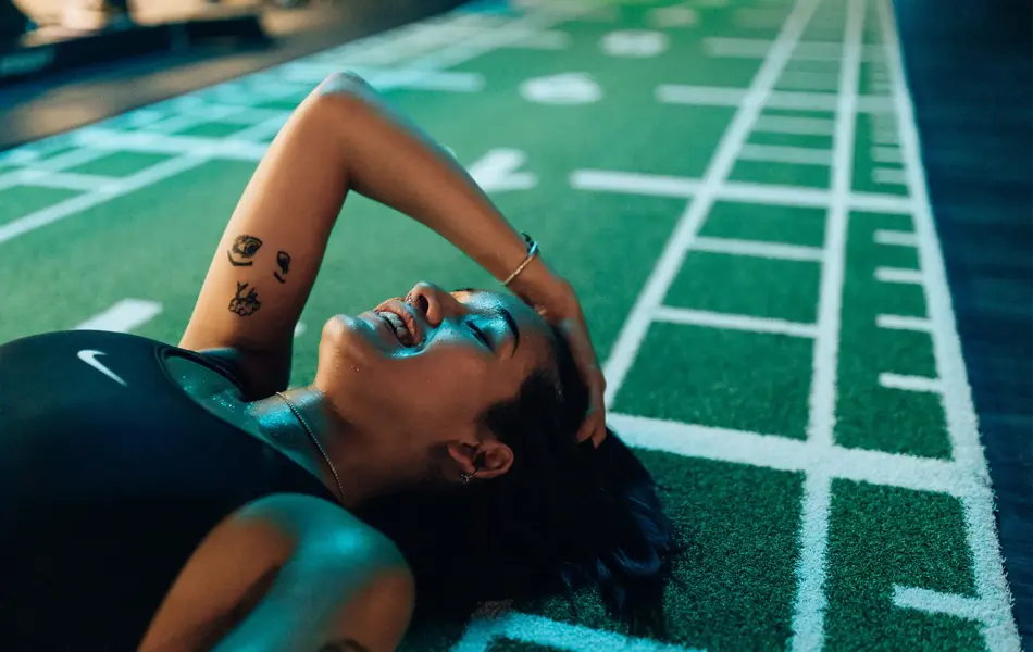 smilende svett dame som ligger på gulvet i et treningssenter i sort sportsbh