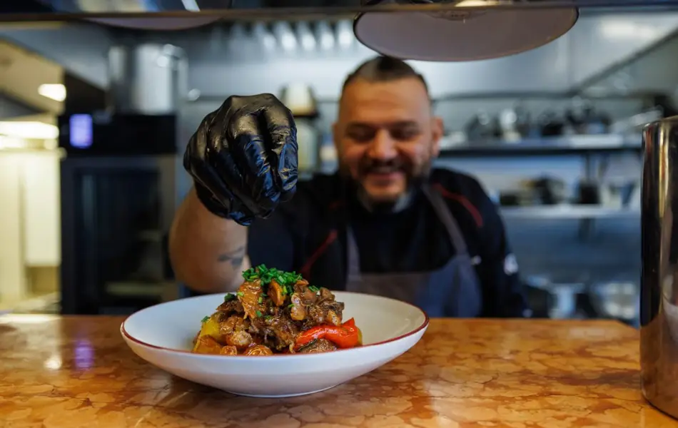 Man smiler foran en tallerken med mat