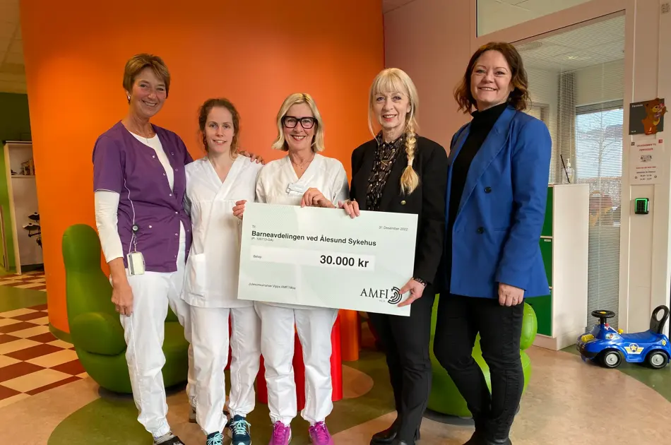 Fem damer holder en gaveskjekk til Barneavdelingen ved Ålesund sykehus