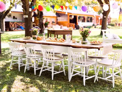 Table set for a garden party or celebration outside. Flowers and sweet and savoury snacks on the decorated table in the garden.