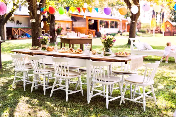 Table set for a garden party or celebration outside. Flowers and sweet and savoury snacks on the decorated table in the garden.