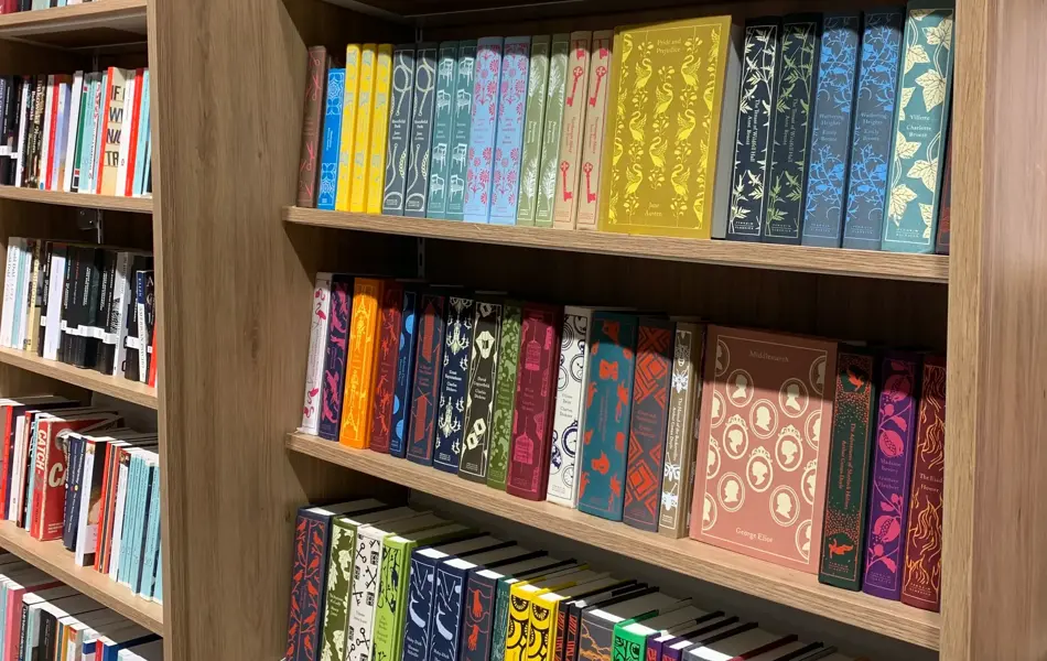 Norli med eikebokhyller fra gulv til tak fylt med bøker i ulike sjangre