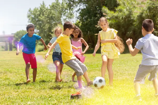 Cheerful children are jogning with ball on the playground
