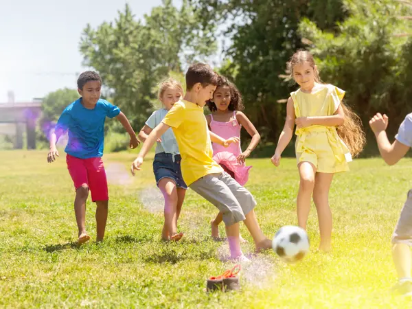 Cheerful children are jogning with ball on the playground