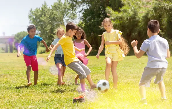 Cheerful children are jogning with ball on the playground