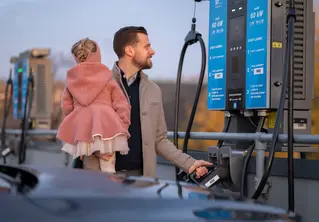 Far med barnet på armen som prøver å sette fra seg ladekabelen 