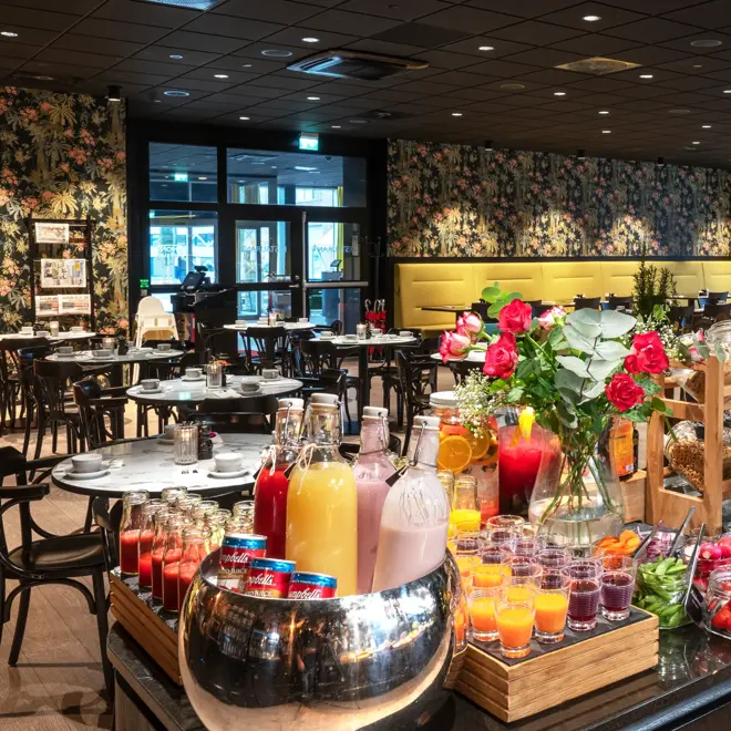 Frokostbuffet, frokostsal med runde spisebord, tapetvegg med blomster, vindu, gule gardiner. 