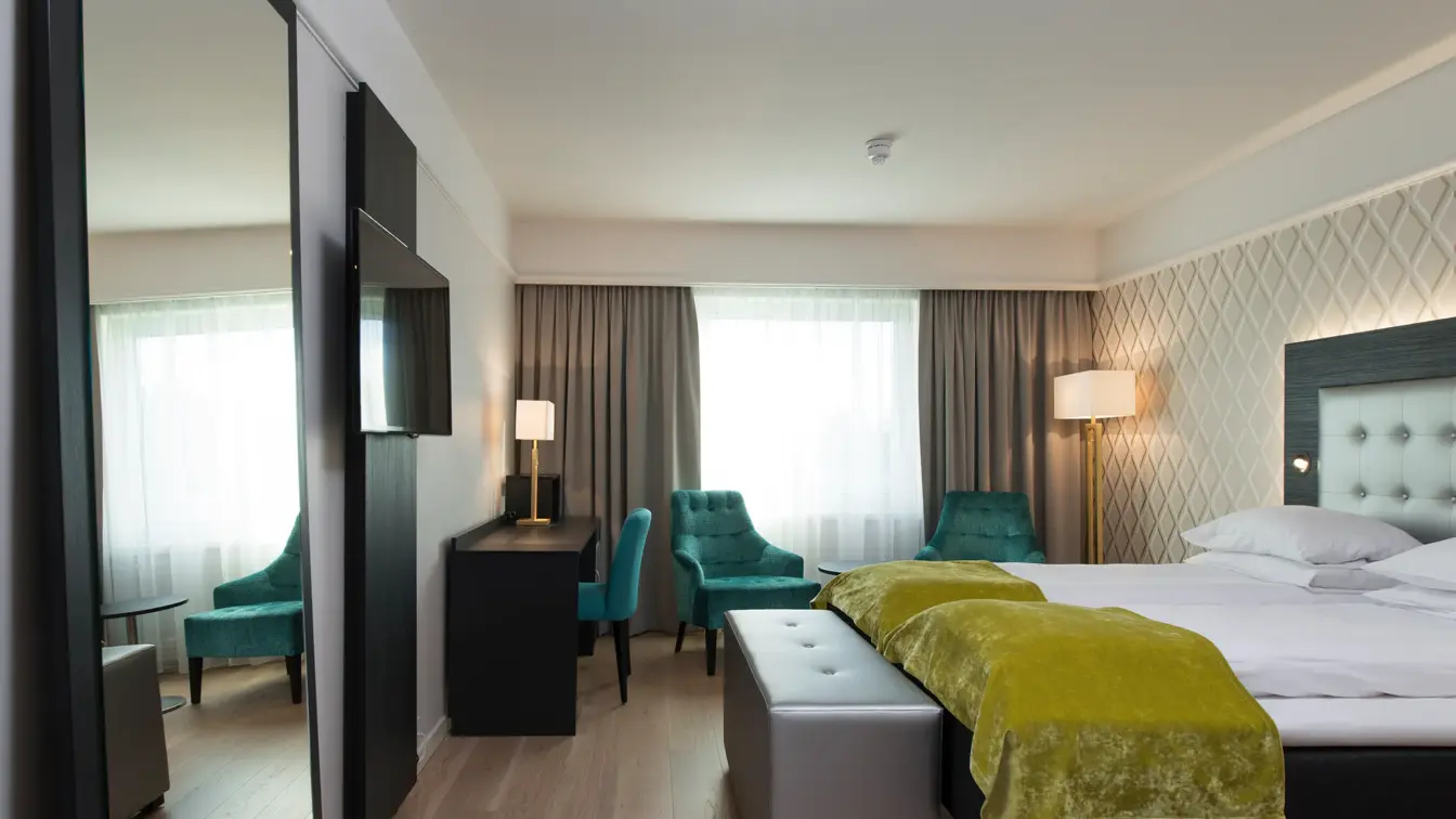 Dobbeltseng med to lenestoler og arbeidspult i superior room på Thon Hotel Oslofjord i Sandvika