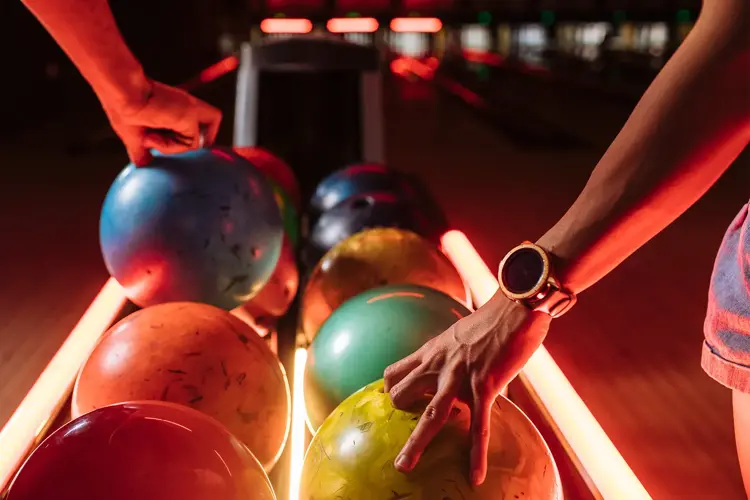 Bowlingkuler på rekke i grønn, oransje, blå og rosa