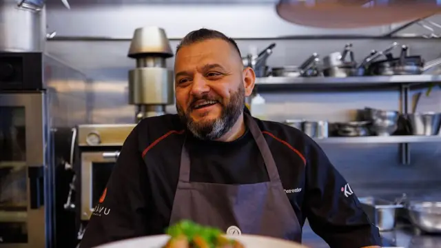 Man ler foran en tallerken med mat