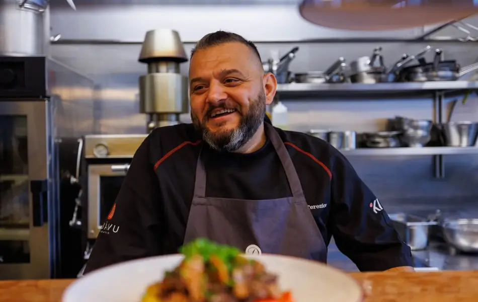 Man ler foran en tallerken med mat