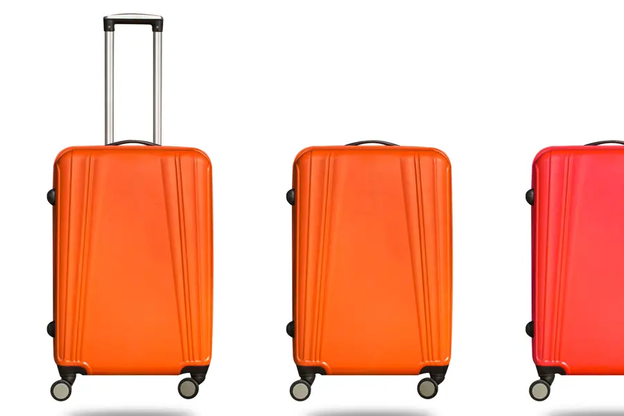 Tre oransje kofferter med hjul