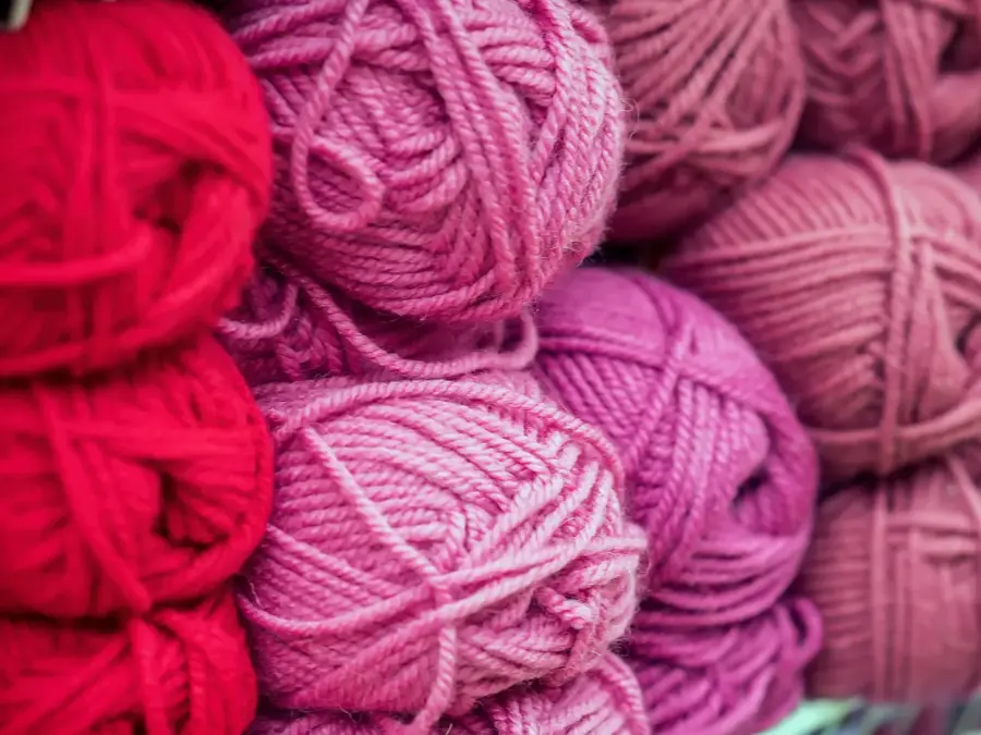 Variegated pile of knitting yarn for knitting in shades of purple, pink, violet. Store of goods for creativity and needlework. Colored multicolored yarn for knitting. Store shelves for craftsmen