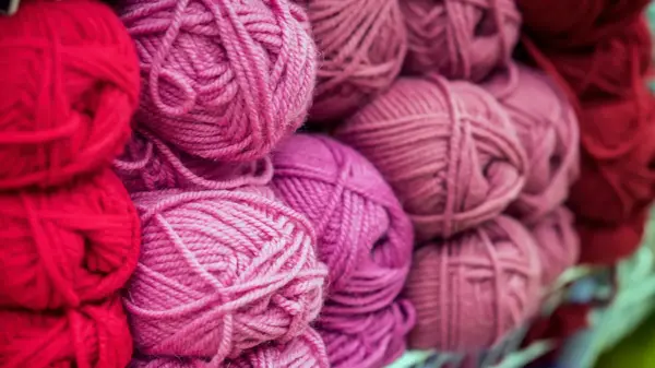 Variegated pile of knitting yarn for knitting in shades of purple, pink, violet. Store of goods for creativity and needlework. Colored multicolored yarn for knitting. Store shelves for craftsmen