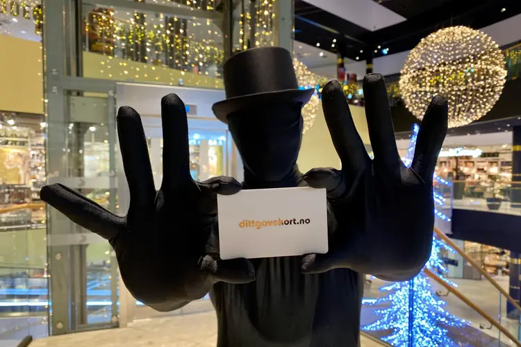 Mann i sort drakt holder fram et gavekort