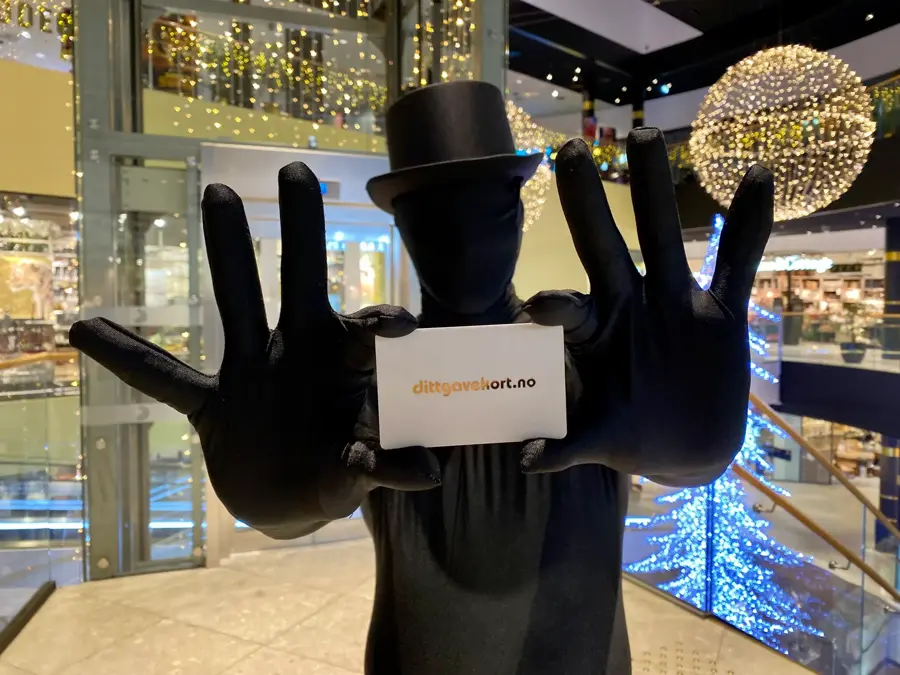 Mann i sort drakt holder fram et gavekort