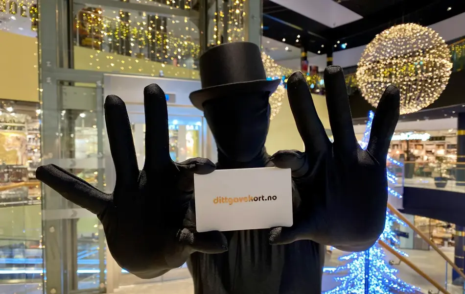 Mann i sort drakt holder fram et gavekort