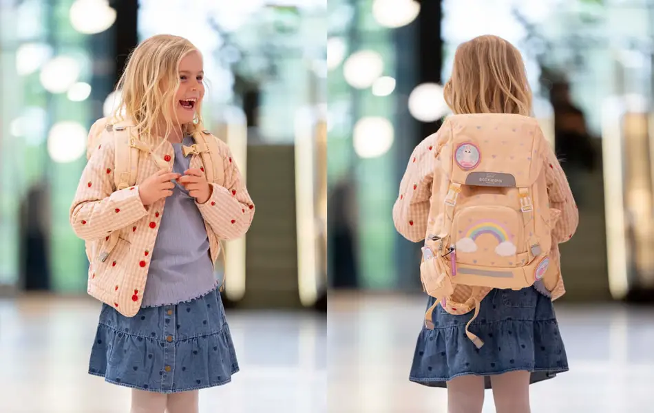 Jente med ytterjakke, olaskjørt, topp og skolesekk smiler og ser til siden. jente med ryggen mot kamera med lysegul skolesekk.