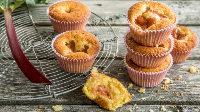 Seks lyse rabarbramuffins på fat og et trebord