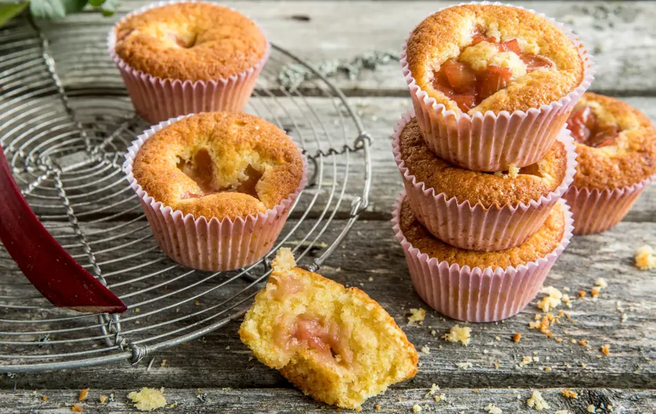 Seks lyse rabarbramuffins på fat og et trebord