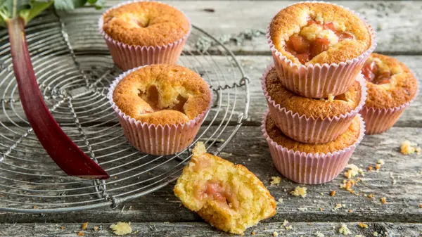 Seks lyse rabarbramuffins på fat og et trebord
