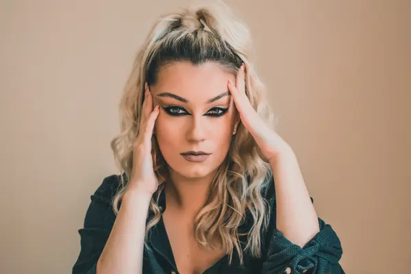 Kvinne med oppsatt hår og reversed cat eye-sminke som ser i kamera