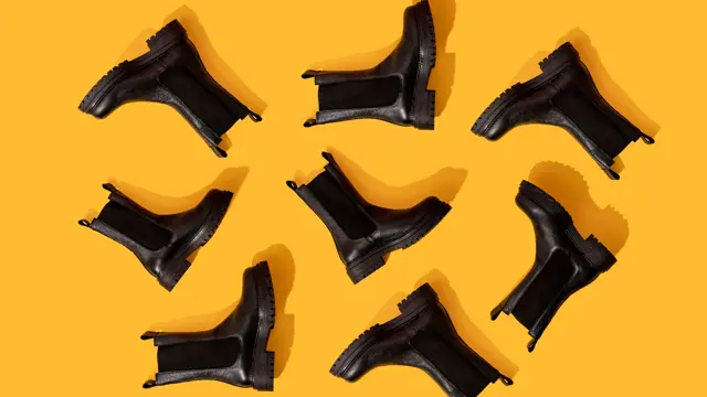 Svarte Chelsea-boots på oransje underlag i studio.